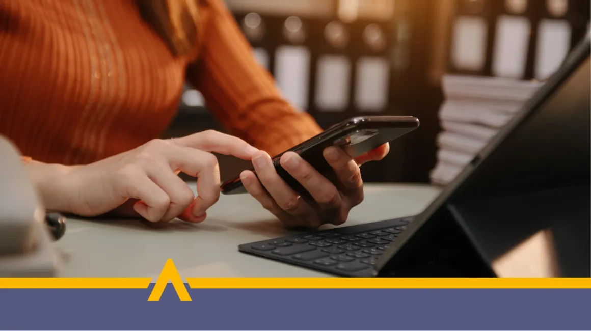 Osoba wpisująca dane na smartfonie w miejscu pracy